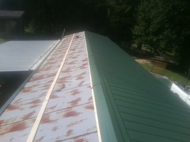 Old rusted panels beside newly installed green metal roofing — Wind Damage Roof Repair by Roofing Brothers in Huntington Station
