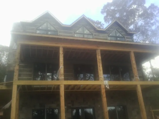 Dormers and porch framing on a large log home under construction — Roof Coating work by our crew in Huntington Station