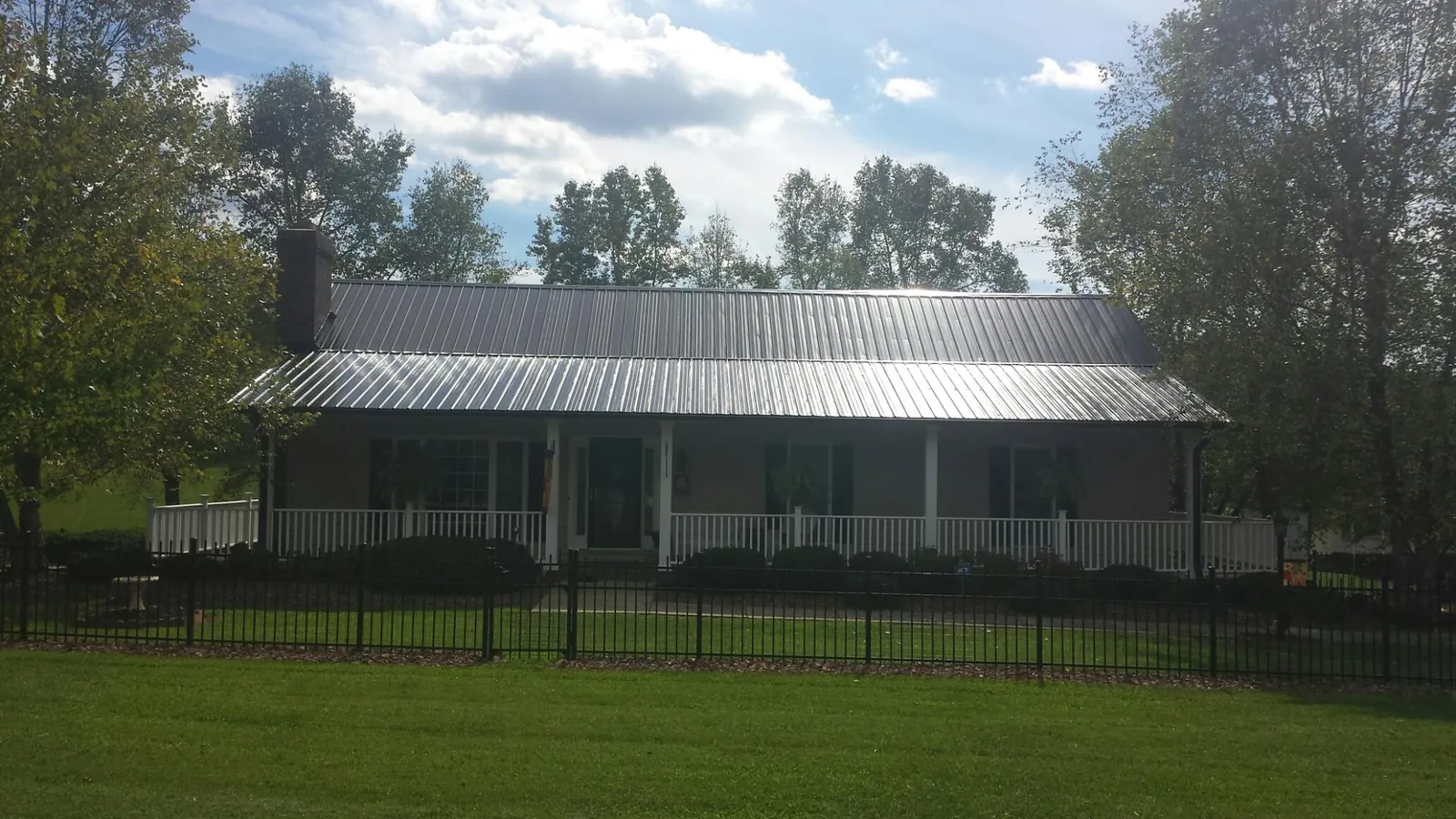 Gray metal roof on a brick ranch with a full width front porch — Gutter Guard Installation work by our crew in Huntington Station