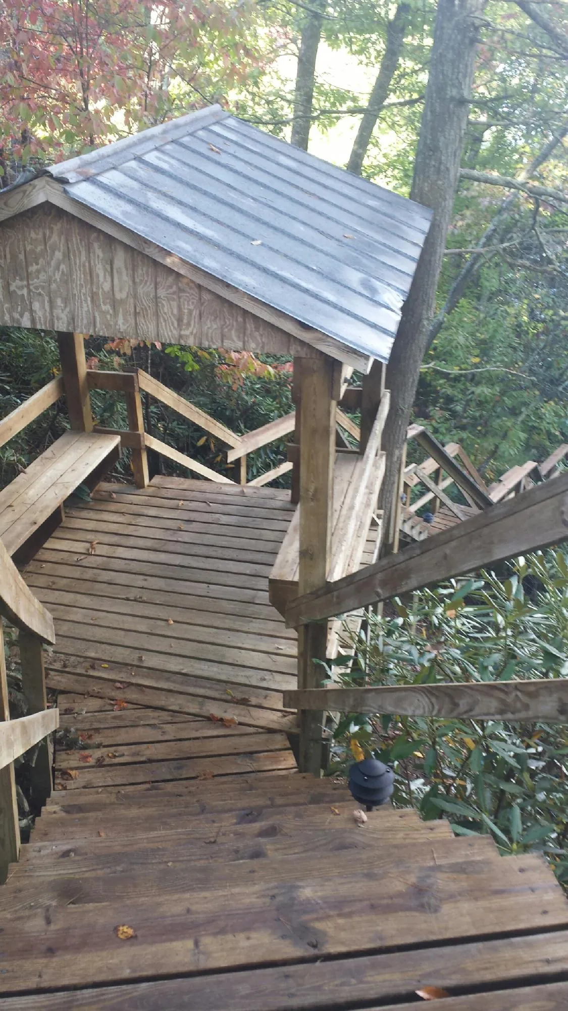 Metal roofed shelter over wooden steps on a wooded walkway — Skylight Repair & Installation work by our crew in Huntington Station