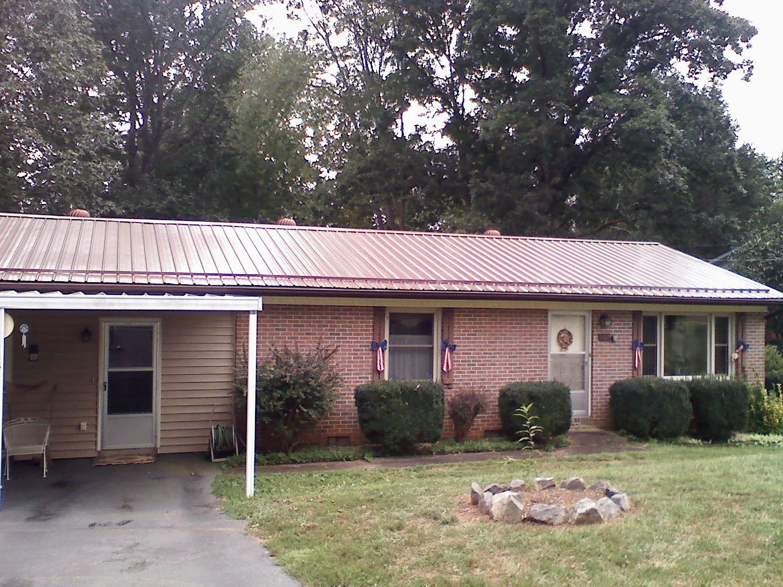Bronze metal roof and carport on a brick ranch home — Roof Repair work by our crew in Huntington Station