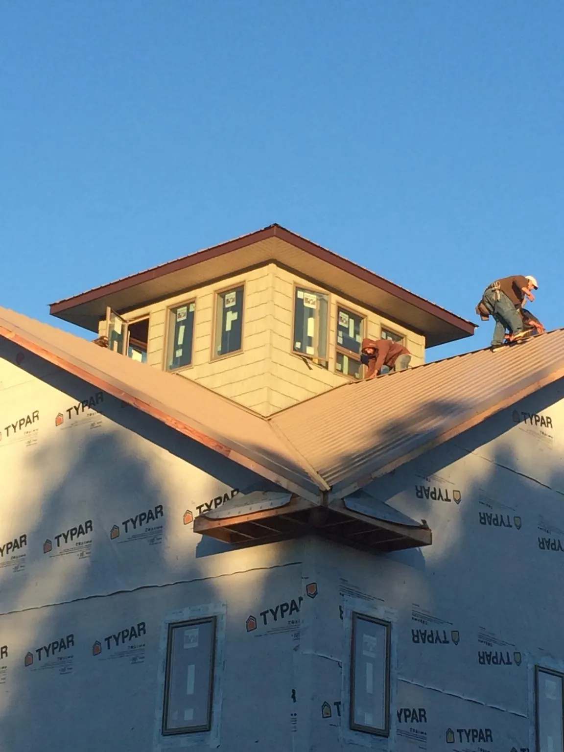 Roofers working around a rooftop cupola on a new metal roof at sunset — Roof Waterproofing in Huntington Station by Roofing Brothers